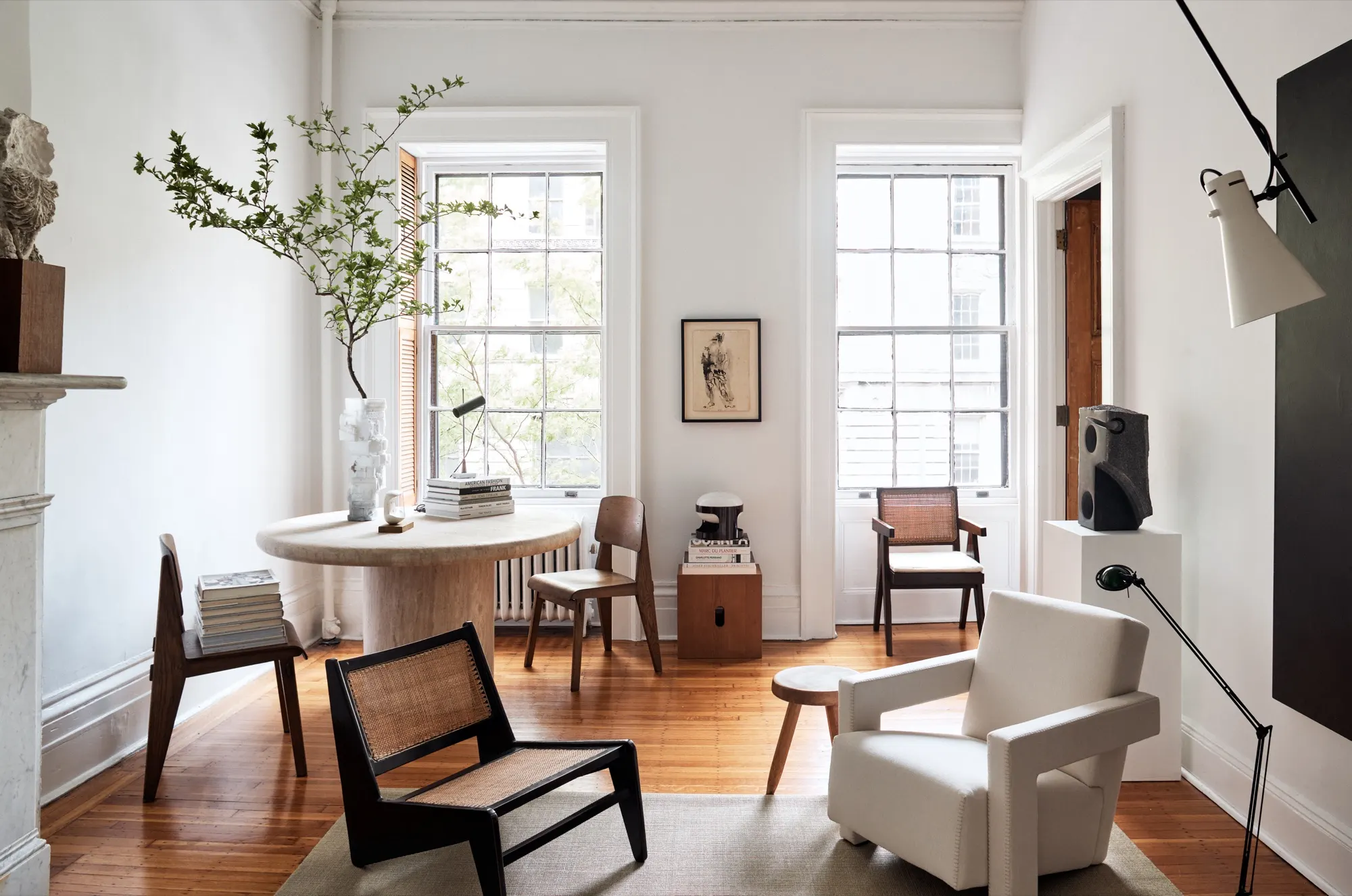Living room interior — round travertine table, woven chair, tall windows
