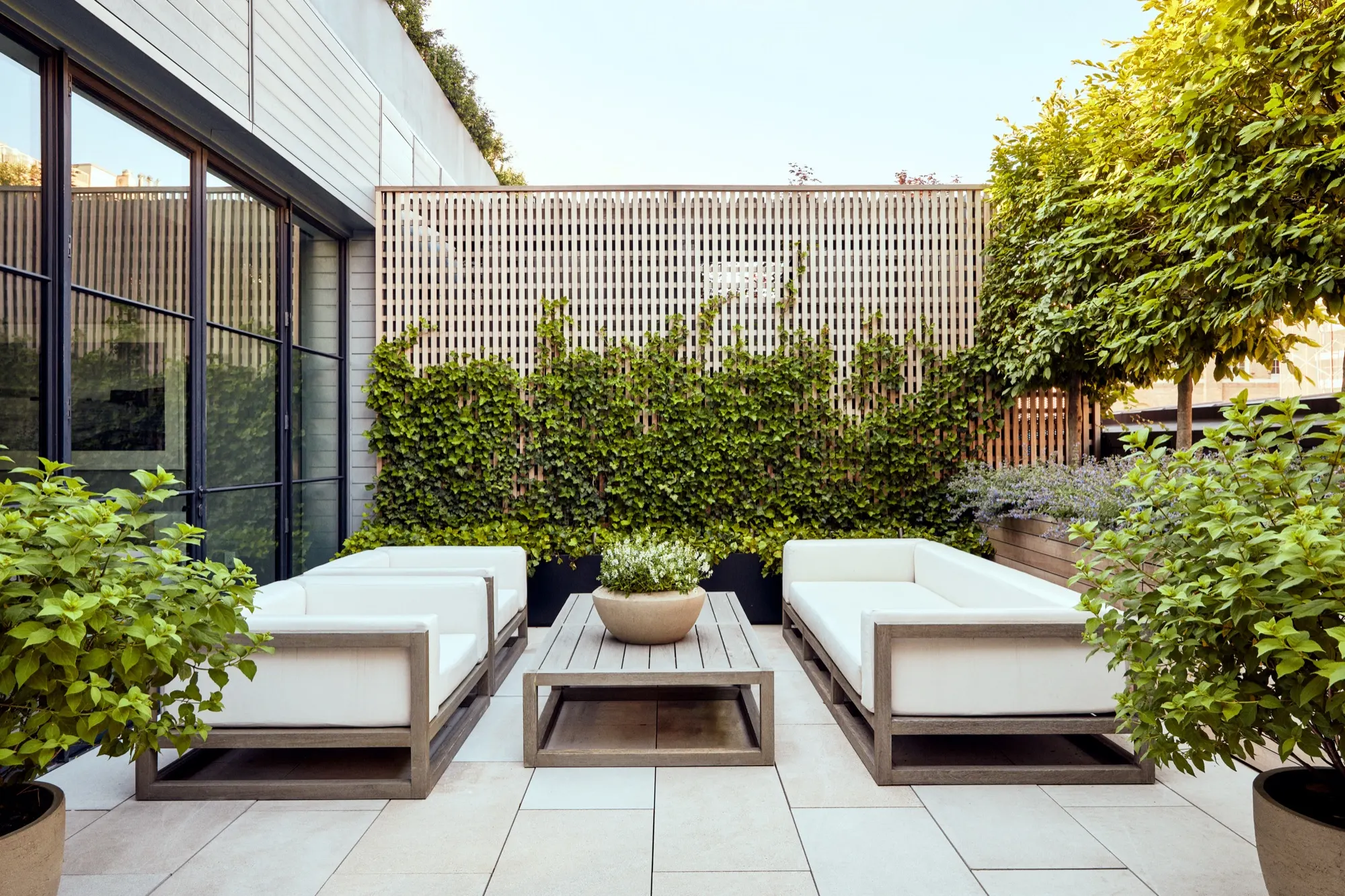Outdoor patio with white sofas, ivy trellis, planters