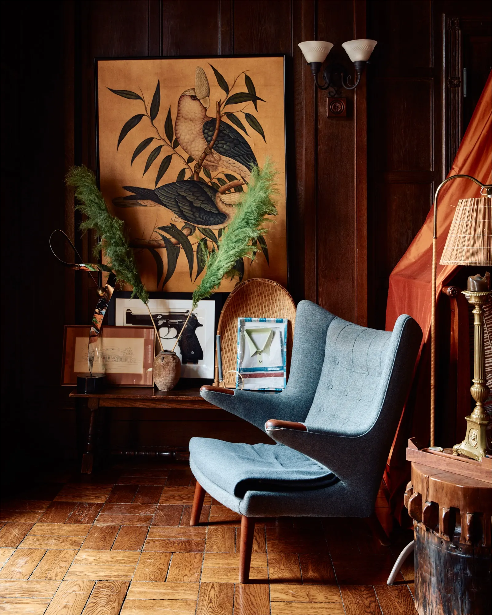 Dark wood-paneled room with blue armchair and herringbone floor